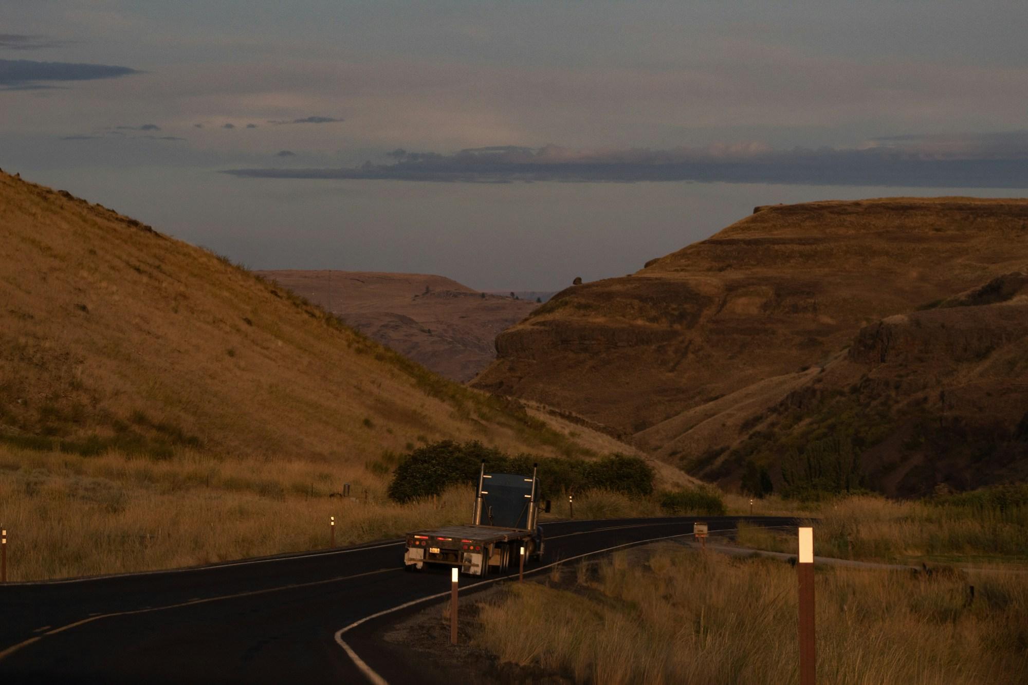 Flatbed trailer running a winding road at dusk