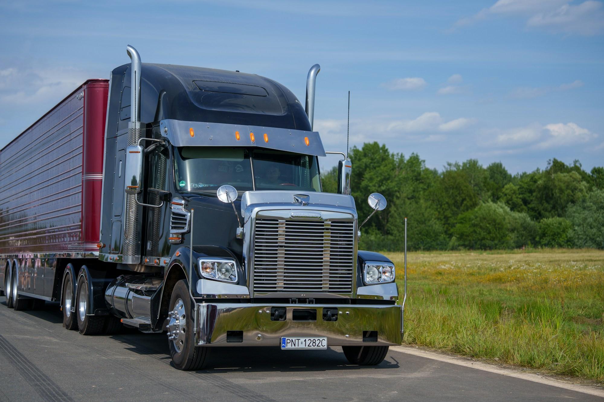 Semi-truck with a red trailer on a rural highway