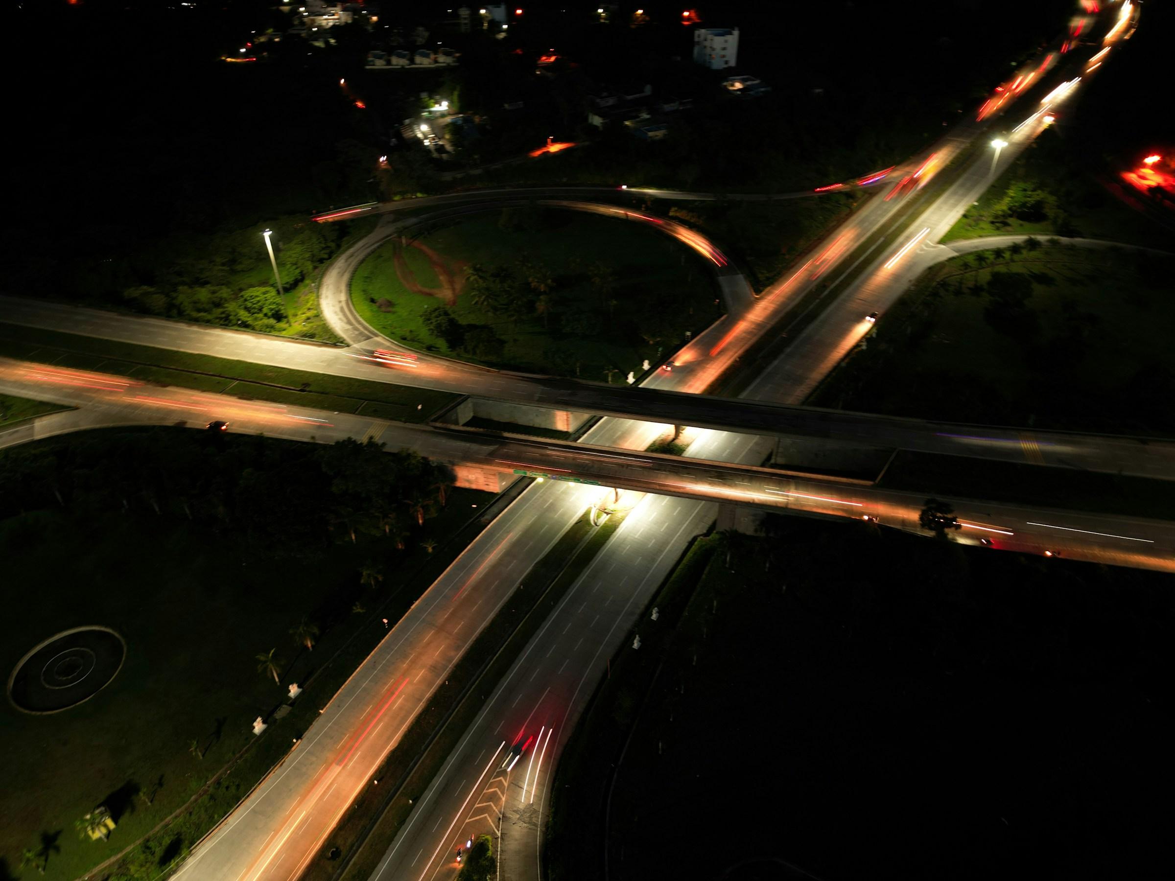 Aerial view of a highway interchange at night with light trails