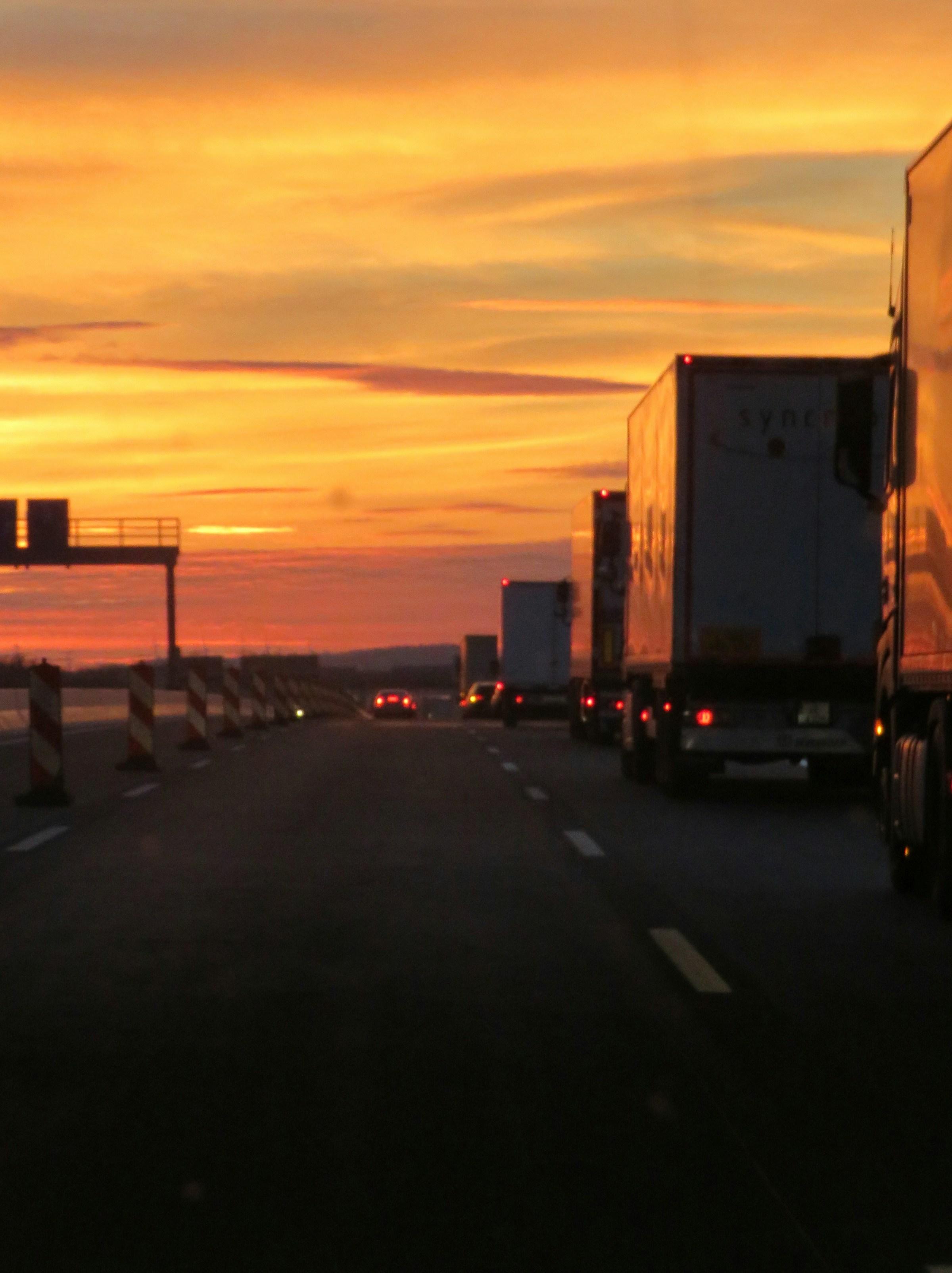 Convoy of freight trucks running the highway at golden hour